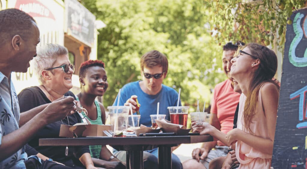 Group of friends enjoying food and drinks outdoors at a restaurant, highlighting El Segundo’s vibrant dining scene.
